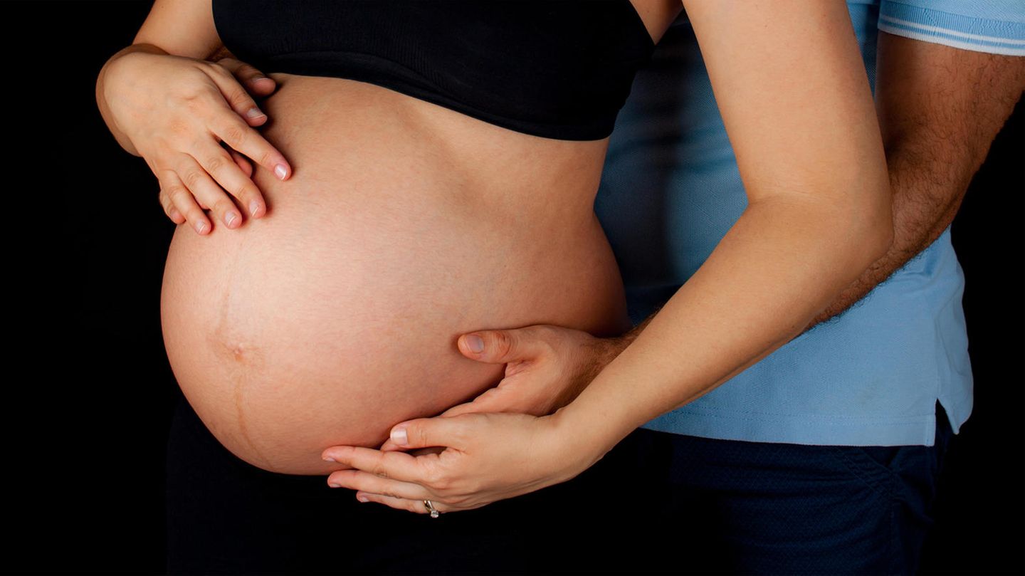 Eine Schwangere fasst sich auf den nackten Bauch