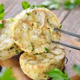 Semmelknödel  Rund 4 Portionen, Arbeitszeit: rund 40 Minuten  Zutaten für 4 Portionen  6 Brötchen, altbackene (Semmeln), 3 EL gehackte Petersilie,  10 g Butter, 1 fein gehackte Zwiebel, 250 ml Milch, 3 Eier, Salz und Pfeffer, evtl. Semmelbrösel zum Binden  Zubereitung:  1. Die Brötchen in kleine Würfel oder in dünne Scheiben schneiden.  2. Die gehackte Petersilie und die Zwiebel in der Butter ganz kurz anschwitzen, aber keine Farbe nehmen lassen, dann mit den Brötchenwürfeln mischen.  3. Die Milch bis kurz vorm Kochen erhitzen und über die Brotwürfel gießen. Etwa 10 Minuten quellen lassen. Die mit Salz und Pfeffer verquirlten Eier dazugeben und alles zu einem nicht zu festen Teig verrühren. Sollte der Teig doch zu weich sein, etwas Semmelbrösel einrühren, kein Mehl verwenden.  4. Mit nassen Händen tennisballgroße Knödel formen und in der siedenden, aber nicht sprudelnd kochenden Flüssigkeit (Salzwasser oder Brühe) in 20 Minuten gar ziehen lassen, bis sie nach oben steigen. Semmelknödel sind die ideale Beilage zu Gulasch, Schweinebraten oder auch geschmorten Pilzen.