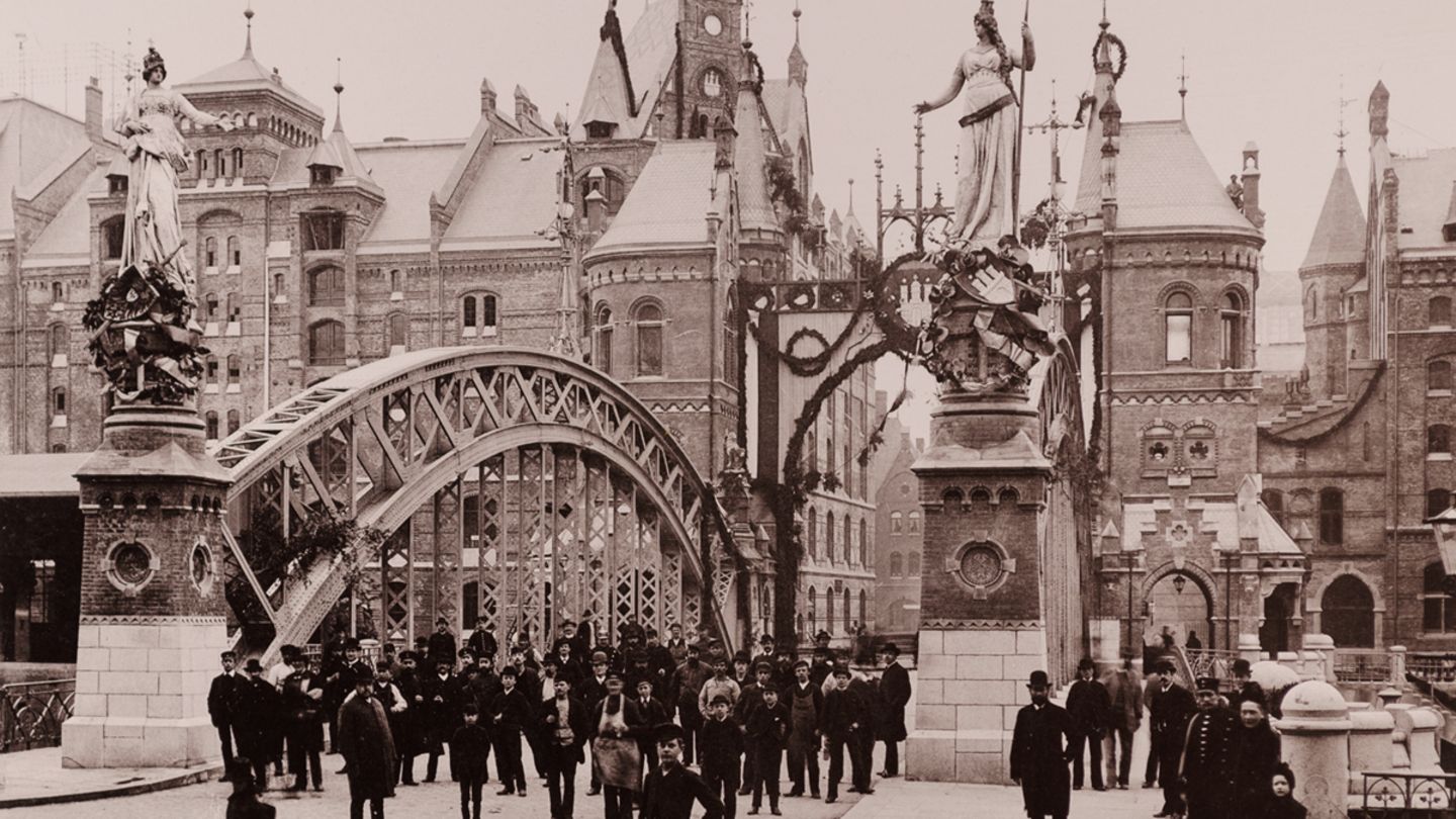 Eine Menschenansammlung an der Brooksbrücke im November 1888. Im Hintergrund die Lagerhäuser der Speicherstadt.