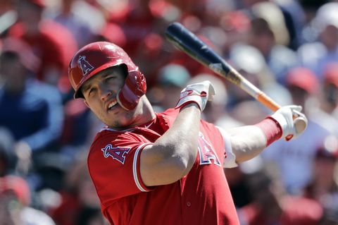 Ein Mann in rotem Baseball-Trikot und Helm lässt nach einem Schlag den Baseballschläger in seiner linken Hand ausschwingen