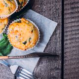 Deftige Eier-Muffins      Zutaten:   Bacon (1 bis 2 Scheiben pro Muffin)  Toast (1 Scheibe pro Muffin)  Eier (je eins pro Muffin)  Salz  Schnittlauch      Zubereitung:   Die Vertiefungen eines Muffinblechs einfetten. In einer Pfanne einige Scheiben Bacon anbraten (für jenen Muffin eine), währenddessen ein paar Scheiben Scheiben (Vollkorn-)-Toast leicht rösten. Mit einem schmalen Glas oder Dessertring (in der Größe des Muffinbodens) Böden aus dem Brot ausstechen und je einen Boden in die Vertiefung legen. Den noch heißen Speck wie einen Ring in die Mulde legen. Er bildet den Rand. In jede Vertiefung ein Ei schlagen, mit etwas Salz würzen und im heißen Ofen 12 bis 15 Minuten backen, je nachdem, wie weich das Ei noch sein soll. Herausholen, kurz abkühlen lassen, mit Pfeffer und vielleicht noch Schnittlauch würzen und servieren. Alternativ können Sie auch je einen ganzen Toast in die Mulde drücken, dann aber vorher das Brot dünn ausrollen. Weitere alternative oder ergänzende Zutaten: frische Kräuter, Schinkenwürfel, geriebener Käse oder Gemüsestücke wie Erbsen, Tomaten, Paprika oder Zwiebeln, bei Bedarf gewürfelt.