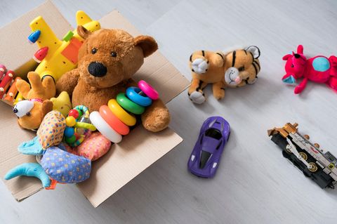 Ein Teddy sitzt in einer Box voll Spielsachen.