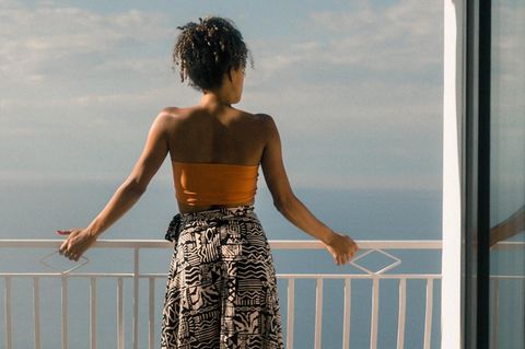 Eine Frau steht an einem Geländer und blickt auf das Meer