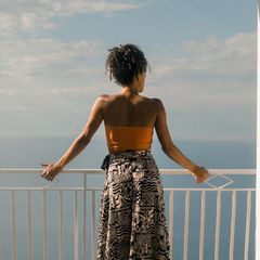 Eine Frau steht an einem Geländer und blickt auf das Meer