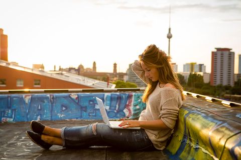 Frau sitzt auf Terrasse mit Computer