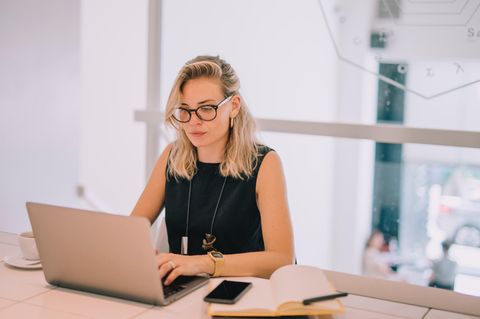 Frau mit Brille tippt auf einem Laptop