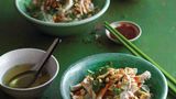 Nudelsalat mit Hühnchen-Pho      Zutaten:  ½ TL feines Meersalz, 1 l Brühe aus der schnellen Hühnchen-Pho (Bild 1), 2 ½ EL Zucker, 1 EL Sriracha-Sauce plus mehr zum Servieren, 2 EL nicht gewürzter japanischer Reisessig, 3 EL normale Sojasauce, 1 ½ EL Rapsöl oder ein anderes neutrales Öl, 2 TL fein gehackter Knoblauch oder ¾ TL Pho-Gewürz ,1 ½ TL Maisstärke, in 2 TL Wasser gelöst, 300 g getrocknete mittelflache Reisbandnudeln, Fischsauce, 350 g gekochtes Huhn aus einem Hühnchen-Pho-Rezept, 2 grüne Zwiebeln (nur grüne Teile), in dünne Scheiben geschnitten, 60 g Kopfsalat oder ein anderer zarter Blattsalat, in schmale Streifen geschnitten (Rippen intakt lassen), 5 g grob gehacktes frisches Koriandergrün (nur obere zarte Stängel), 10 g grob gehackte frische Minz- oder Thai-Basilikum-Blätter, 40 g ungesalzene geröstete Erdnüsse, grob gehackt, etwa 35 g gebratene Schalotten oder Zwiebeln, selbst gemacht oder gekauft      Zubereitung:  Salz, Zucker, Chilisauce, Essig und Sojasauce in 120 ml Brühe einrühren, dann diese Mischung neben den Herd stellen. Das Öl und den Knoblauch oder die Gewürzmischung in einen kleinen Stieltopf geben. Bei mittlerer bis geringer Temperatur erhitzen, bis der Knoblauch brutzelt und hellblond ist (nach 3 bis 4 Minuten) oder bis die Gewürzmischung ein wenig duftet (nach 1 Minute). Die Pfanne vom Herd nehmen und etwa 15 Sekunden leicht abkühlen lassen; dann die Saucenmischung hineingießen. Bei hoher Temperatur aufkochen. Die Maisstärke umrühren, dann in die Sauce rühren. Sobald diese dick wird, nach etwa 15 Sekunden, auf eine kühle Platte schieben und vor Gebrauch 10 Minuten stehen lassen. Das ergibt etwa 240 ml. Inzwischen die Nudeln in einem Topf mit Wasser 5 bis 7 Minuten kochen, bis sie weich sind, aber noch Biss haben (Anleitung auf der Packung beachten). Abgießen, unter fließendem Wasser rasch abkühlen, dann beiseitestellen und erneut abgießen und abkühlen lassen. Die restliche Brühe (etwa 840 ml) kosten und nach Bedarf mit Fischsauce würzen, damit sie angenehm pikant schmeckt. Dann die Brühe in einem Stieltopf bei mittlerer Temperatur wieder erhitzen.  In der Zwischenzeit das Huhn in mundgerechte Stücke schneiden oder reißen und, wenn nötig, im Mikrowellenherd aufwärmen. Im Idealfall enthält das Huhn etwas Saft. Beiseitestellen. Zum Anrichten vier Reisschalen für die Brühe und vier Suppenschalen für den Salat verwenden. Ein wenig grüne Zwiebel in jede Schale geben (der Rest kommt in den Nudelsalat). Neben die Brühe stellen. Den Kopfsalat auf die Suppenschalen verteilen. Einen Teil der Nudeln und des Huhns dazugeben, dann etwa 60 ml der Sauce. Darauf die restliche grüne Zwiebel, Koriandergrün, Minze (oder Basilikum), Erdnüsse und gebratene Schalotten (oder Zwiebeln) verteilen. Die heiße Brühe in die Reisschalen schöpfen. Sofort mit den Nudelsalatschalen servieren. Die Gäste auffordern, die Bestandteile ihres Salats mit Löffel und Essstäbchen zu vermengen und die Brühe als wohltuendes Intermezzo zu genießen. Wenn die Nudeln zu viel Sauce enthalten, einen Löffel Brühe hineingießen. Den Gästen, die Schärfe schätzen, extra Chilisauce anbieten.
