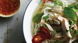 Schnelle Hühnchen-Pho      Zutaten:  2 cm langes Stück Ingwer, 2 mittelgroße grüne Zwiebeln, 1 sehr kleines (15 g) Büschel Koriandergrün, grob gehackt, 1 ½ TL Koriandersamen, 1 ganze Gewürznelke, 840 ml bis 1 Liter natriumarme Hühnerbrühe, 1 Hühnerbrust (180 bis 225 g) oder 1 Schlegel ohne Knochen und Haut, etwa ½ TL feines Meersalz, 150 g getrocknete Reisbandnudeln, 2 bis 3 TL Fischsauce, etwa ½ TL Zucker oder 1 TL Ahornsirup (optional), frisch gemahlener schwarzer Pfeffer (optional)      Zubereitung:  Den Ingwer schälen und in 4 oder 5 Münzen schneiden. Mit einem Fleischklopfer oder der flachen Seite eines Messers flach klopfen und beiseitestellen. Die grünen Teile der grünen Zwiebel in dünne Scheiben schneiden (ergibt 2 bis 3 EL) und zum Garnieren beiseitestellen. Restliche Teile in kleinfingerlange Stücke schneiden, zerquetschen, dann in den Ingwer mischen. Die feinen Stängel des Koriandergrüns grob hacken (ergibt 2 EL) und zum Garnieren beiseitestellen. Die restlichen Stängel beiseitestellen. Koriandersamen und Gewürznelke in einem 3- bis 4-Liter-Topf bei mittlerer Hitze rösten, bis sie nach 1 bis 2 Minuten duften. Ingwer und grüne Zwiebel dazugeben. Etwa 30 Sekunden umrühren, bis die Mischung aromatisch ist. Den Topf von der Platte schieben, 15 Sekunden warten, damit er etwas abkühlt, dann die Brühe hineingießen. Den Topf wieder auf die Platte stellen, dann Wasser, Korianderstängel, Huhn und Salz dazugeben. Bei hoher Temperatur aufkochen, dann die Temperatur reduzieren und die Mischung 30 Minuten leicht köcheln lassen. Während die Brühe köchelt, die Reisnudeln in heißem Wasser einweichen, bis sie weich und opak sind. Abgießen, spülen und beiseitestellen. Nach 5 bis 10 Minuten Köcheln sollte das Huhn fest und durchgegart sein (auf Fingerdruck sollte es nachgeben). Das Huhn in eine Schüssel legen, mit kaltem Wasser übergießen, um das Kochen zu beenden, dann abgießen. Abkühlen lassen, dann in mundgerechte Stücke schneiden oder hacken. Locker zudecken, damit es nicht austrocknet. Wenn die Brühe fertig ist, durch ein feines Maschensieb in einen 2-Liter-Topf gießen. Das Sieb mit Musselin auskleiden, damit die Brühe sehr klar wird. Feste Partikel wegwerfen. Das ergibt etwa 1 Liter. Wenn nötig, mit Fischsauce und Zucker (oder Ahornsirup) würzen, um eine starke pikant-süße Note zu erhalten. Die abgeseihte Brühe bei mittlerer bis hoher Temperatur aufkochen. Die Nudeln 5 bis 60 Sekunden in einem Nudel- oder Maschensieb in die heiße Brühe tauchen, damit sie heiß und weich werden. Dann aus dem Topf nehmen und auf die zwei Schalen verteilen. Die Hitze reduzieren, damit die Brühe heiß bleibt, während Sie das Huhn auf den Nudeln arrangieren und mit den gehackten grünen Zwiebeln, dem Koriandergrün und einer Prise Pfeffer garnieren. Kosten und bei Bedarf zum letzten Mal salzen. Die Brühe erneut aufkochen und in die Schalen schöpfen. Mit Extras genießen, die Ihnen schmecken.