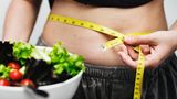 Gesunde Ernährung: Bauch mit einem Maßband und eine Schüssel Salat
