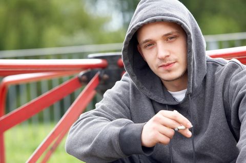 Ein Jugendlicher raucht auf einem Spielplatz