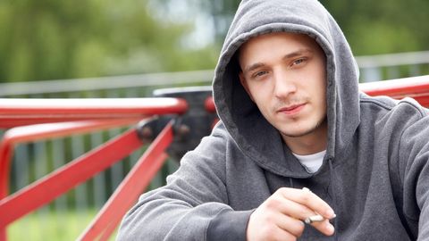 Ein Jugendlicher raucht auf einem Spielplatz