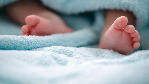 Die Füße eines Säuglings gucken aus einer blauen Decke