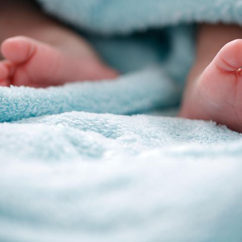 Die Füße eines Säuglings gucken aus einer blauen Decke