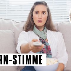 Junge Frau auf dem Sofa mit Popcorn und Fernbedienung