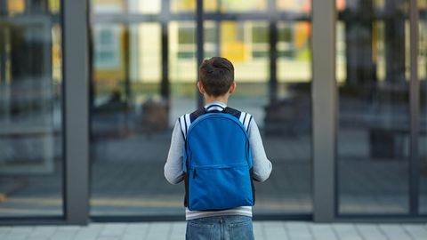 Kind mit Ranzen vor der Schule