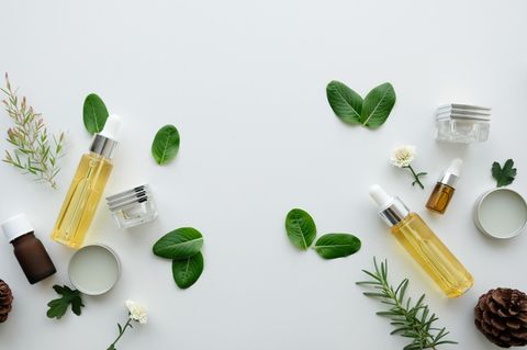 Kosmetikprodukte, Blätter, Blüten und Tannenzapfen auf Tisch ausgebreitet