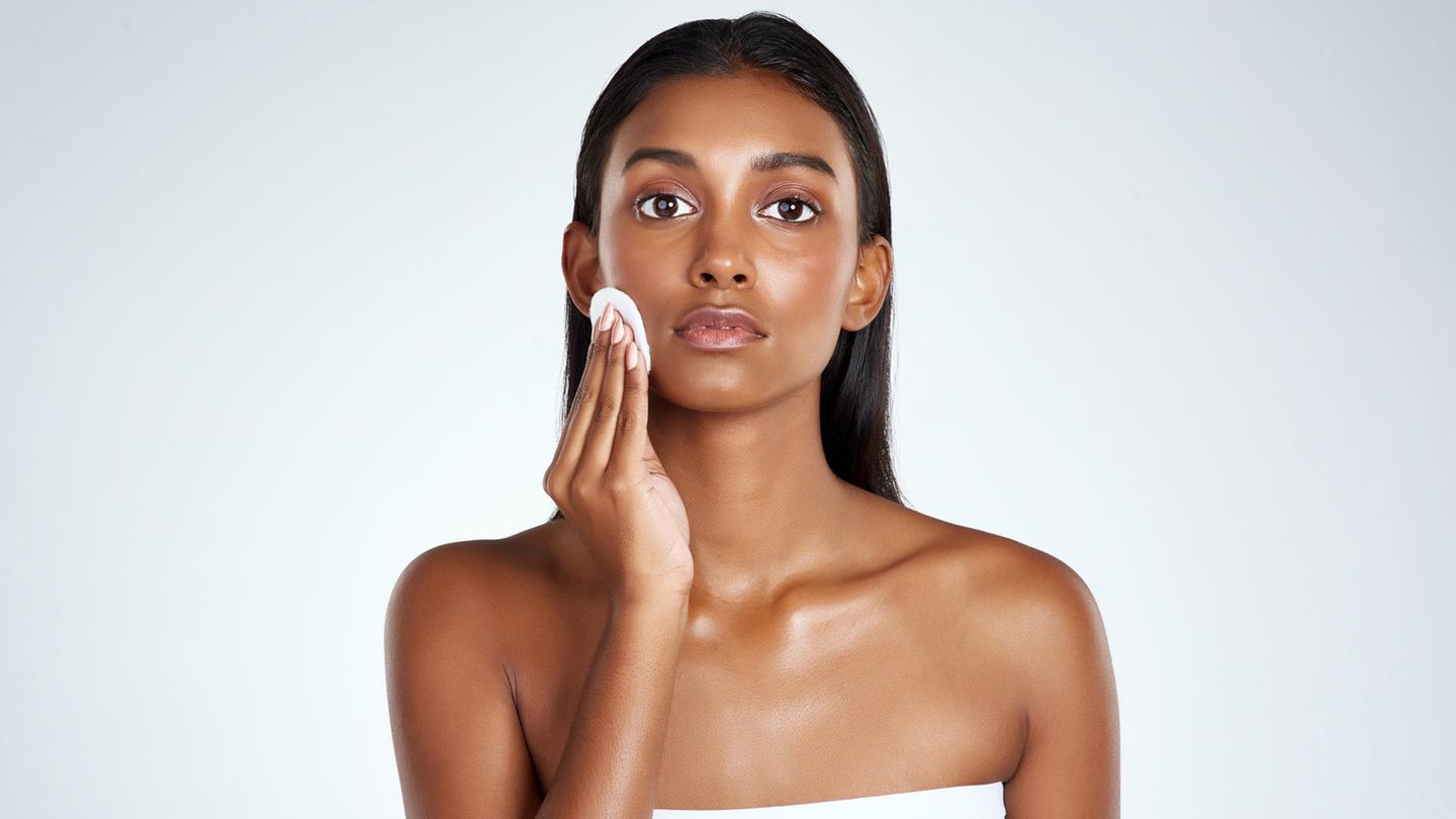 Frau trägt Gesichtstoner mit Wattepad auf