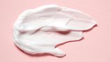 Klecks von Kosmetikcreme auf rosa Oberfläche