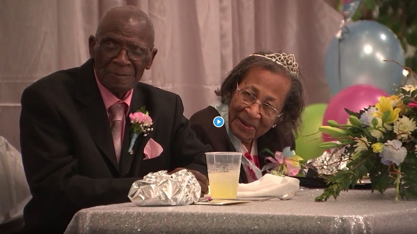 Das Ehepaar sitzt nebeneinander und lächelt, die Ehefrau trägt ein Diadem