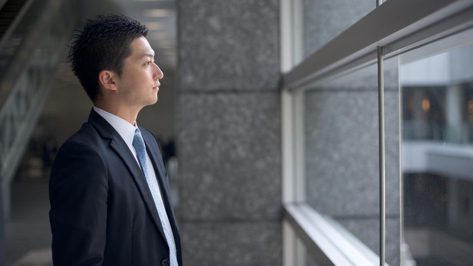 Ein Japanischer Geschäftsmann schaut aus dem Fenster