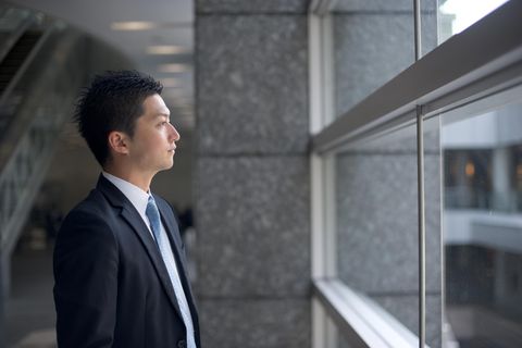 Ein Japanischer Geschäftsmann schaut aus dem Fenster