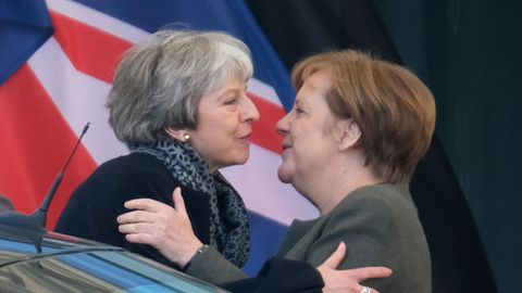 Theresa May und Angela Merkel umarmen sich zur Begrüßung vor dem Bundeskanzleramt. Davor ein Auto, dahinter der Union Jack