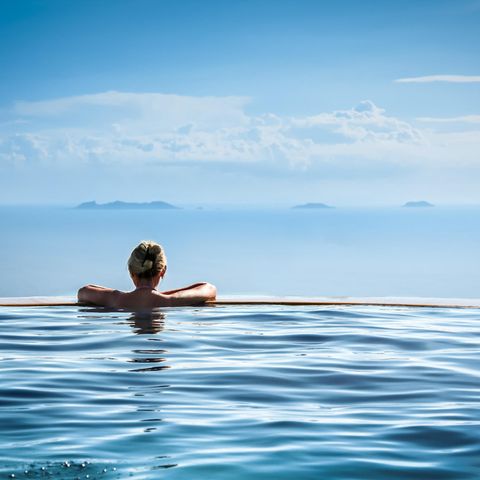 Frau in einem Infinity Pool schaut in die Ferne