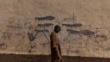 Gewinner in der Kategori Umwelt Stories: Ein Waisenjunge im Tschad vor einer Wand mit gezeichneten Granatwerfern.