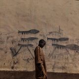 Gewinner in der Kategori Umwelt Stories: Ein Waisenjunge im Tschad vor einer Wand mit gezeichneten Granatwerfern.