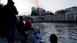 Menschen versammeln sich, verfolgen das Geschehen vom Seine-Ufer aus.