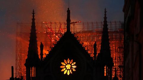 Hinter dem Giebel von Notre Dame mit seinem typischen Rosetten-Fenster erhellt Feuerschein den Himmel über Paris