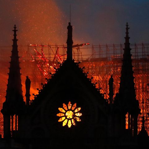 Hinter dem Giebel von Notre Dame mit seinem typischen Rosetten-Fenster erhellt Feuerschein den Himmel über Paris