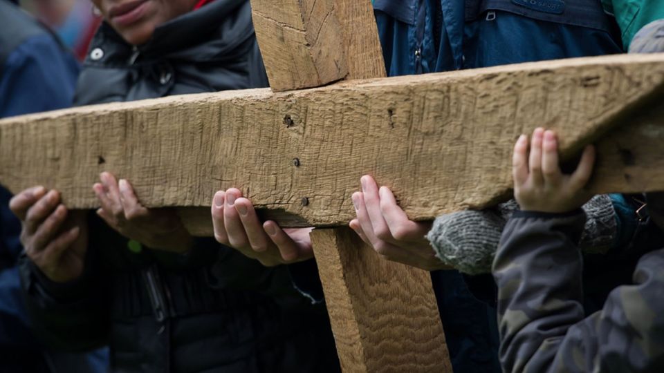 Gläubige halten bei der ökumenischen Kreuzwegprozession am Karfreitag in Lübeck ein großes Kreuz.