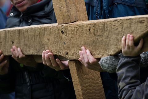 Gläubige halten bei der ökumenischen Kreuzwegprozession am Karfreitag in Lübeck ein großes Kreuz.