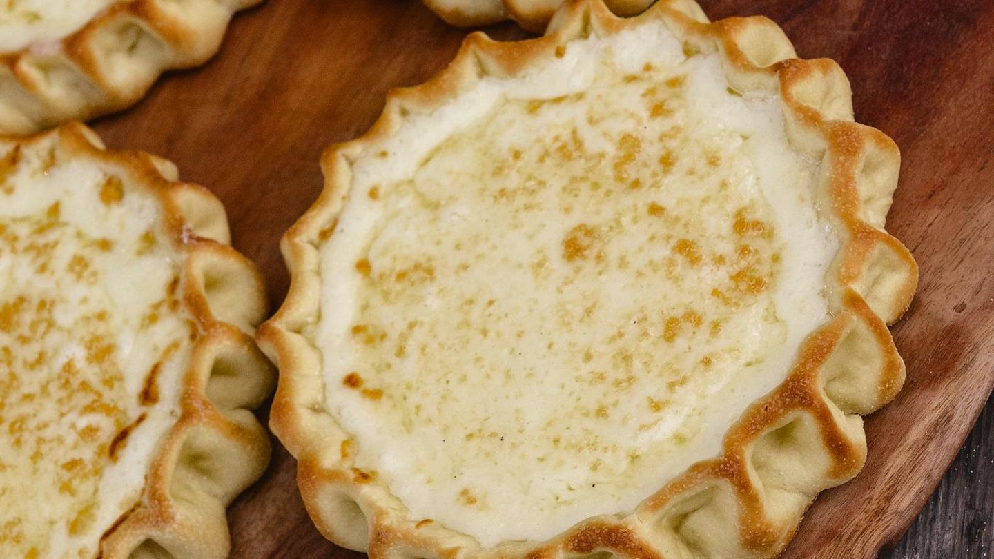 Casadinas al formaggio   Sardische Käsetörtchen   Für ca. 15 Stück · Zubereitung: 30–40 Minuten · Ruhezeit: einige Stunden · Backzeit: 30 Minuten Schwierigkeitsgrad: mittel      Zutaten:  Für den Teig: 400 g Hartweizengrieß, 100 g Schmalz, Salz      Für die Füllung: 500 g frischer Käse (oder Ricotta), gerieben, 100 g Zucker, 2 Eier (Größe M), Abrieb von 1 unbehandelten Zitrone (oder Orange), 100 g Rosinen, 50 g Weizenmehl (Type 405)      Außerdem: etwas Honig zum Bestreichen      Zubereitung:  Hartweizengrieß, Schmalz, etwas Salz und etwas lauwarmes Wasser zu einem geschmeidigen Teig verarbeiten. Diesen mit einem Küchentuch abdecken und einige Stunden ruhen lassen. Den Backofen auf 150 °C Ober-/Unterhitze vorheizen. In einer Schüssel den geriebenen Käse gut mit Zucker, Eiern, Zitronenabrieb und Rosinen vermischen. Etwas Mehl untermischen, damit die Füllung die richtige Konsistenz erhält. Den Teig dünn ausrollen und Kreise mit einem Durchmesser von etwa 10 cm ausstechen. Darauf jeweils einen Löffel der Füllung geben. Die Teigränder etwas hochklappen und an mehreren Stellen zusammenkneifen, um eine Schalenform zu bilden. Die Casadinas auf einem mit Backpapier ausgelegten Backblech platzieren und im vorgeheizten Ofen in etwa 30 Minuten goldbraun backen. Aus dem Ofen nehmen und mit etwas Honig bestreichen. Casadinas werden normalerweise lauwarm serviert.