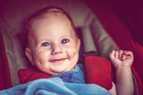 WHO: Ein Baby sitzt im Kinderwagen und lacht