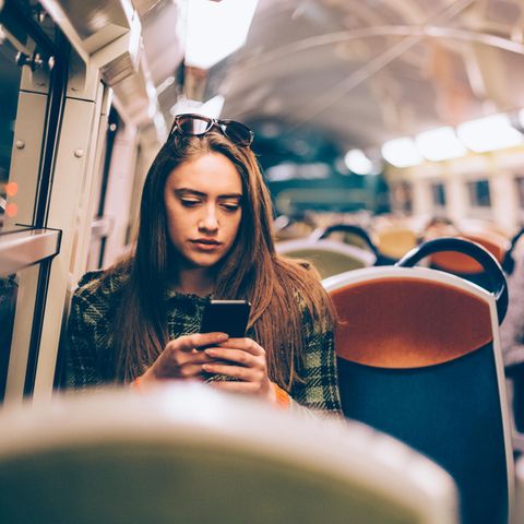 Eine Frau sitzt in der U-Bahn und schaut auf ihr Handy