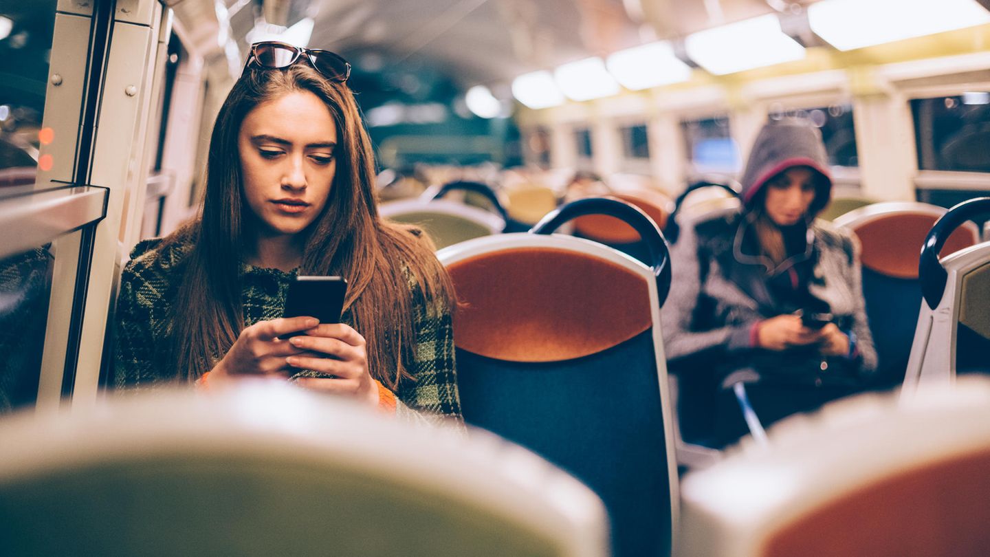 Eine Frau sitzt in der U-Bahn und schaut auf ihr Handy