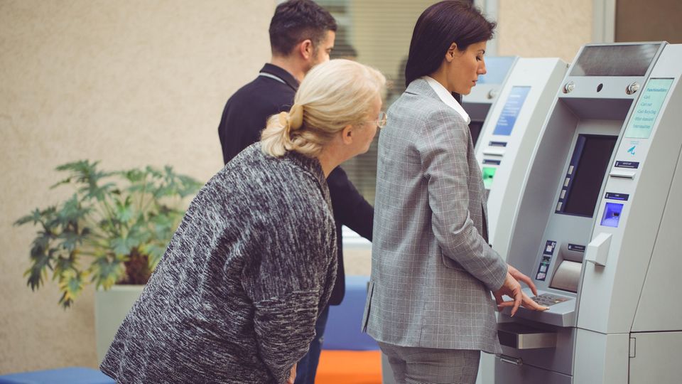 Leute stehen an am Bankautomat