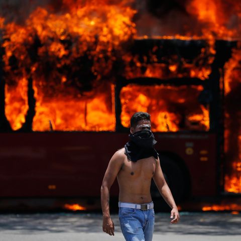 Venezuela, Caracas: Ein Demonstrant geht vor einem Bus