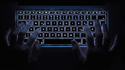 Finger schreiben auf einer leuchtenden Tastatur im Dunkeln