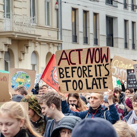 Auf Demo gegen den Klimawandel hält ein Mann ein Schild mit der Aufschrift "Act now before it's too late".