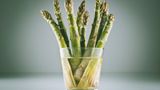 Behandeln Sie Spargel wie Blumen. Stellen Sie diese vertikal in ein Glas Wasser, am besten mit einer Plastiktüte darüber, damit der Spargel keine unangenehmen Küchengerüche annimmt.