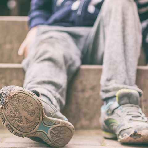 Ein Junge mit kaputten Turnschuhen