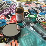 Das ist alles, was du für's Microneedling brauchst: einen Spiegel, 70-prozentigen Alkohol aus der Apotheke, einen Dermaroller und eine Maske oder ein Serum deiner Wahl (diese Platte voller Aufkleber ist übrigens mein Wohnzimmertisch, falls ihr euch fragt, was das soll)