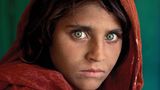 Peschawar (Pakistan), 1984. Das wohl bekannteste Bild von McCurry zeigt Sharbat Gula, in der Welt der Fotografie besser bekannt als "Afghan Girl" (so der Titel der Arbeit). Sharbat Gula wurde um 1972 geboren und durch die Bombardierungen der sowjetischen Armee in Afghanistan zur Vollwaise. In einem Flüchtlingscamp in Pakistan wurde McCurry auf das Mädchen aufmerksam. Er fertigte zwei Porträts des Mädchens an. Das weitaus bekanntere, das zu sehende Bild, wurde 1985 auf der Titelseite von "National Geographic" abgedruckt. Seitdem wurde es millionenfach auf Postern und Buchcovern weltweit gedruckt.