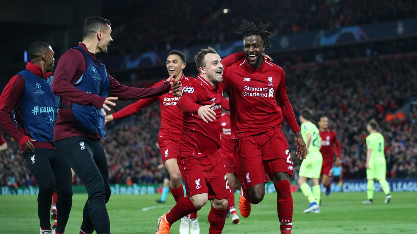 Drei Spieler in Trikots des FC Liverpool laufen jubelnd auf zwei Spieler in Trainingsanzügen zu