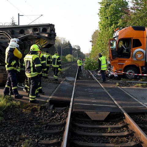 Ein mit einer Ramme beladener Sattelzug steht nach der Kollision mit einem Zug auf einem Bahnübergang
