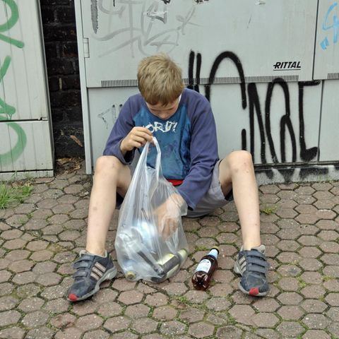 Ein Junge verdient sein Taschengeld durch das Sammeln von Pfandflaschen