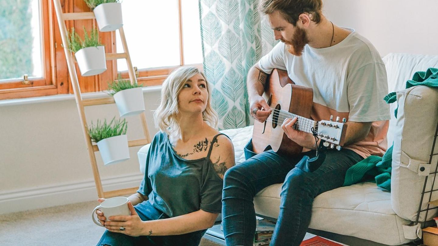 Ein junges Paar, der Mann spielt Gitarre